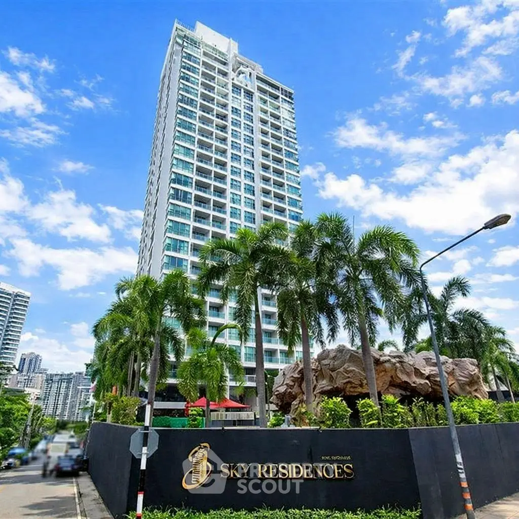 Luxurious Sky Residences building with lush greenery and clear blue sky.