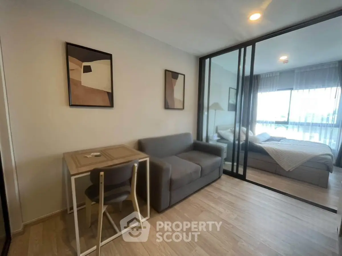 Modern apartment with cozy living room and bedroom separated by glass partition, featuring stylish decor.