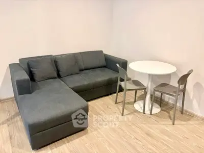 Modern living room with sleek gray sectional sofa and minimalist round dining table.