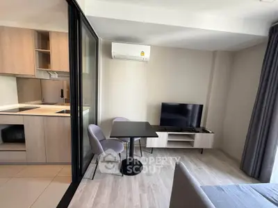 Modern living room with open kitchen, sleek furniture, and air conditioning in a stylish apartment.