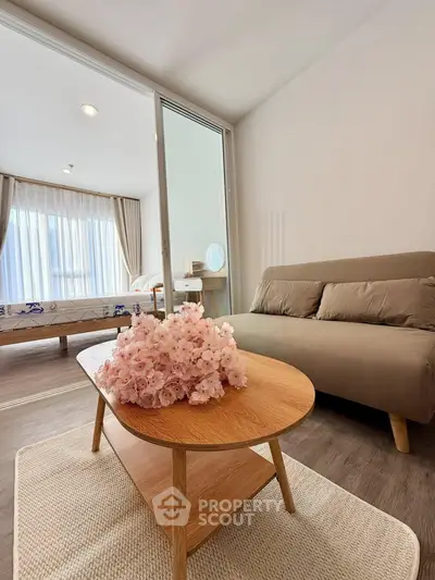 Modern living room with cozy sofa and elegant coffee table, featuring a glimpse of a stylish bedroom.