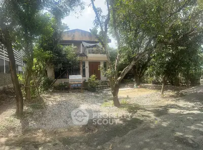 Charming rustic house surrounded by lush greenery and mature trees, offering serene natural ambiance.