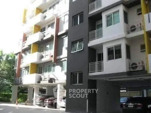 Modern apartment building exterior with parking area and balconies.