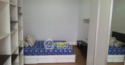 Cozy bedroom with single bed and built-in shelving, perfect for compact living.