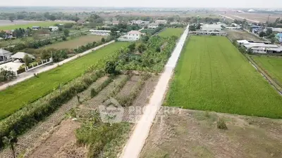 Aerial view of expansive farmland with lush green fields and rural houses.