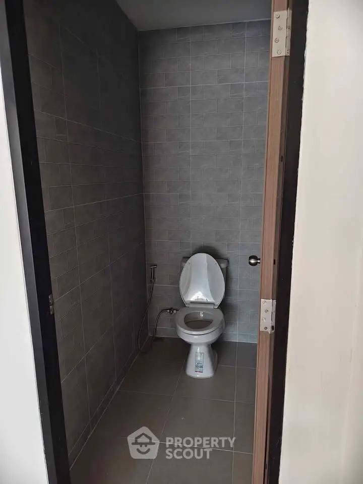 Compact bathroom with modern toilet and tiled walls, ideal for efficient space utilization.