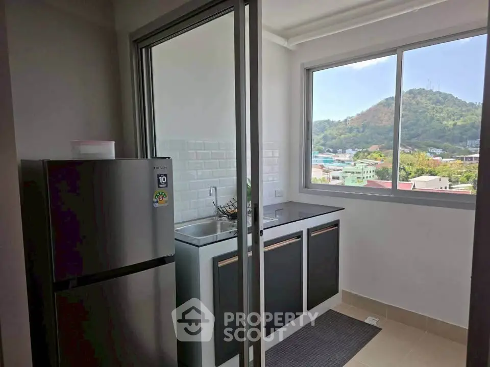 Modern kitchen with mountain view, featuring sleek cabinetry and large window for natural light.