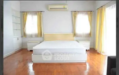Spacious bedroom with hardwood floors and natural light from large windows.