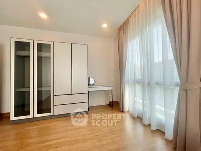 Spacious bedroom with large windows and modern wardrobe in a bright, airy setting.