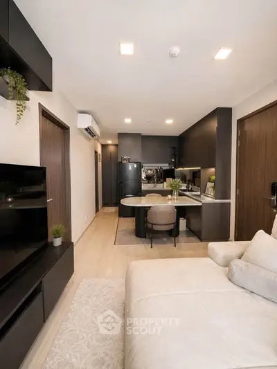 Modern open-plan living room with sleek kitchen, cozy seating, and stylish decor in a contemporary apartment.