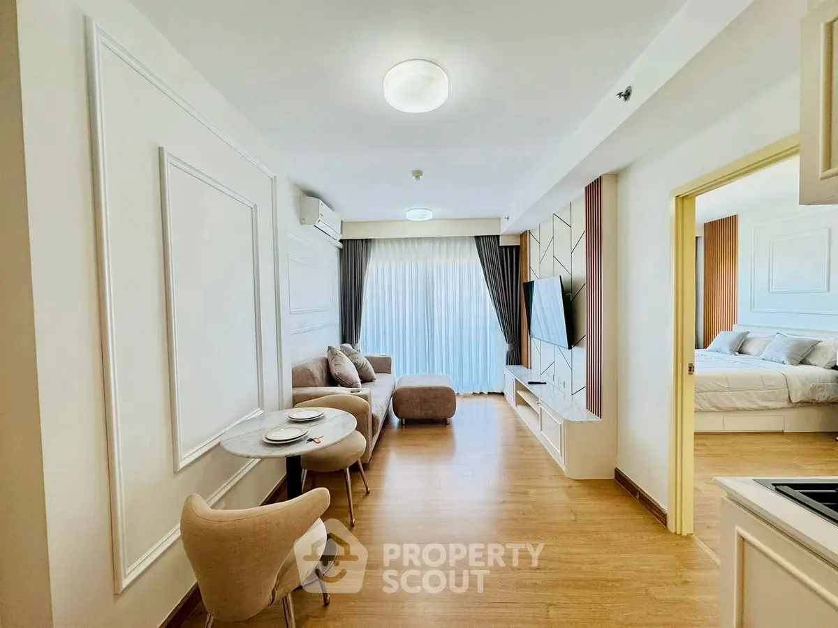 Modern living room with stylish decor and open layout leading to a cozy bedroom.