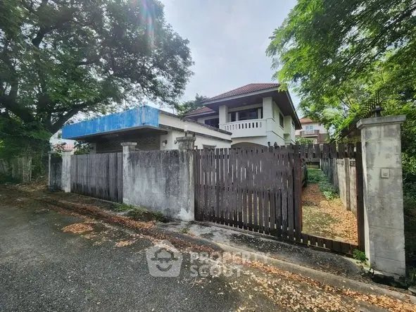 Charming two-story house with a gated entrance and lush greenery, perfect for family living.