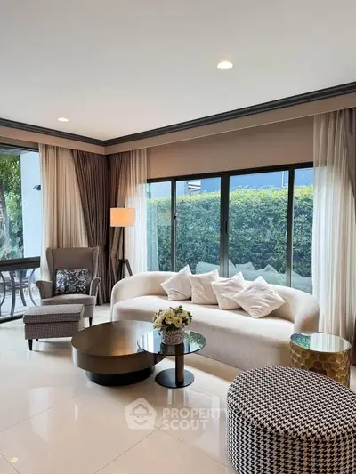 Elegant living room with modern furniture and large windows overlooking lush greenery.