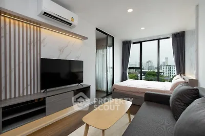 Modern studio apartment with stylish living area and city view, featuring sleek furniture and large windows.