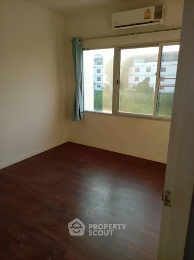 Spacious empty room with wooden flooring and large window view
