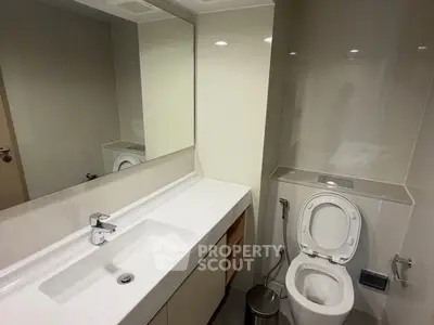 Modern bathroom with sleek fixtures and large mirror in a contemporary apartment.