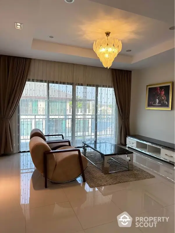 Elegant living room with polished tile flooring, luxurious chandelier, and expansive windows draped in heavy curtains, offering a blend of comfort and sophistication.