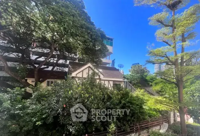 Charming residential building surrounded by lush greenery and vibrant trees, offering a serene urban escape.