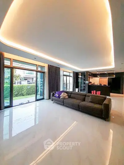 Spacious modern living room with elegant lighting and large windows overlooking a lush garden.