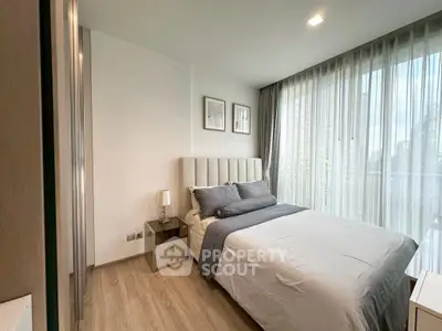 Modern bedroom with large windows and stylish decor in a contemporary apartment.