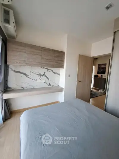 Modern bedroom with stylish marble accent wall and sleek storage cabinets.