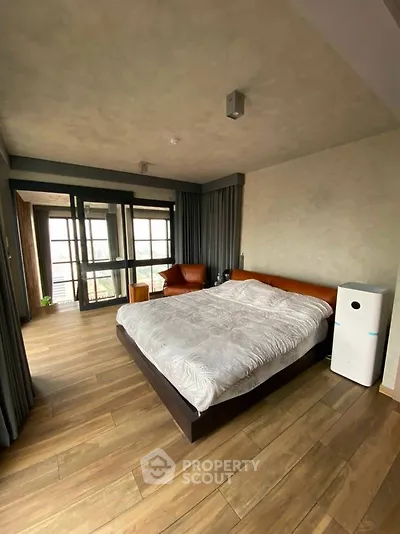 Spacious modern bedroom with wooden flooring and large windows offering natural light.