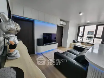 Modern living room with sleek design, featuring a black leather sofa, flat-screen TV, and stylish decor.