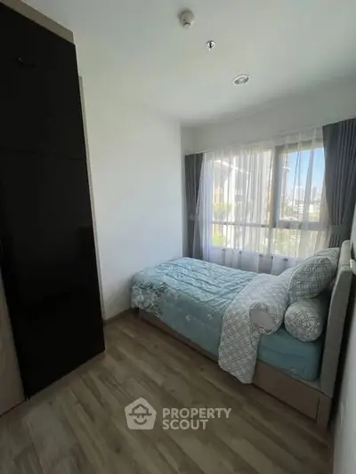 Cozy bedroom with large window and modern decor in a stylish apartment.