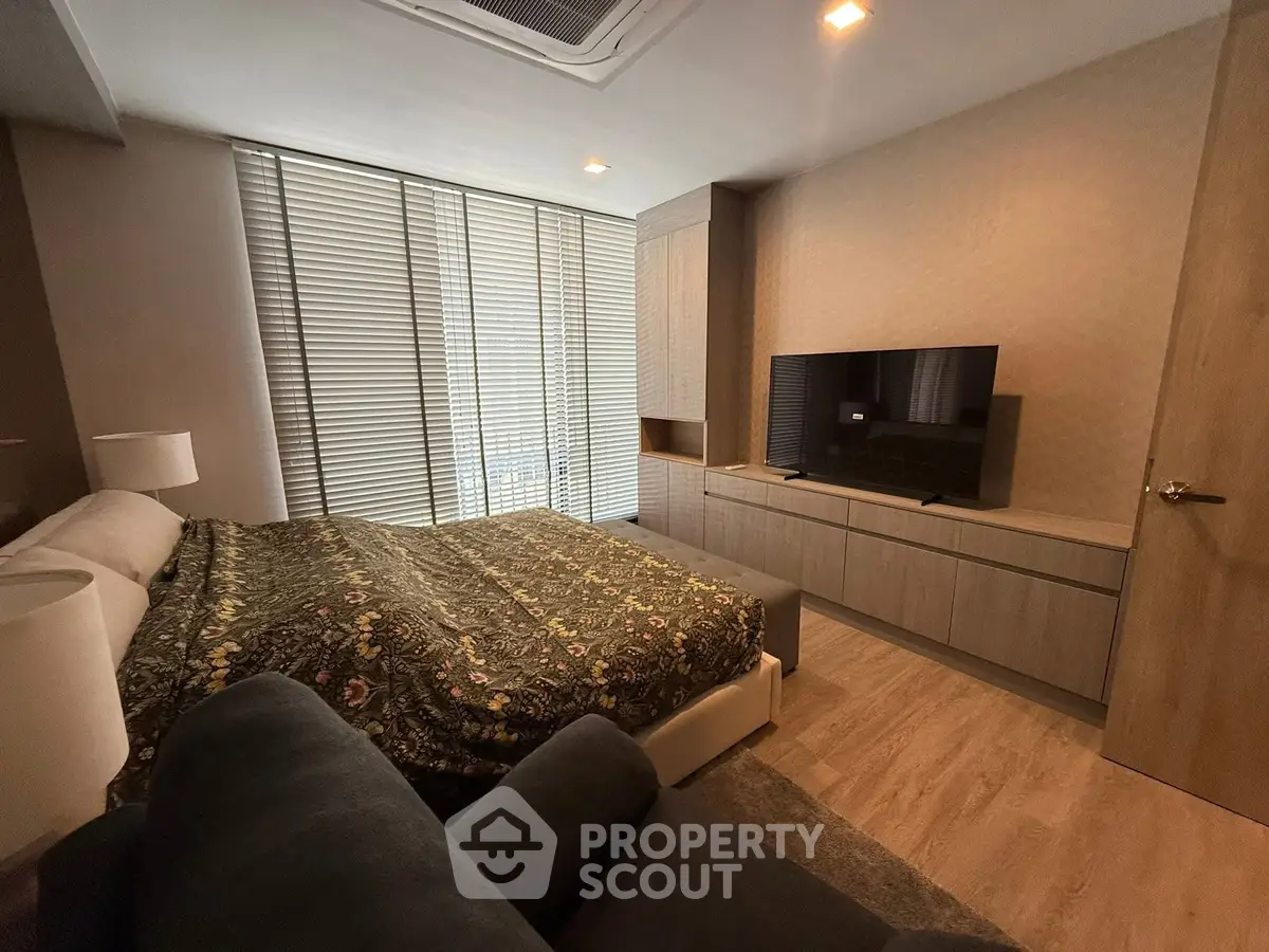 Modern bedroom with stylish decor and large TV, featuring cozy ambiance.