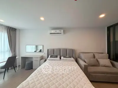 Modern bedroom with cozy bed, stylish sofa, and elegant desk in a bright apartment.