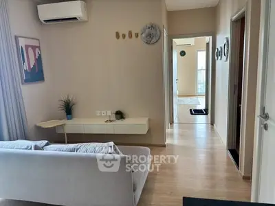 Modern living room with sleek decor and air conditioning, featuring light wood flooring and stylish wall art.