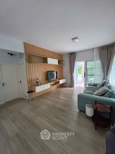 Spacious modern living room with stylish wood paneling and large windows for natural light.