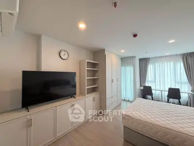 Spacious bedroom with modern furnishings and large windows offering natural light.