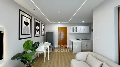 Modern living room with stylish decor and open kitchen layout, featuring sleek furniture and contemporary art.