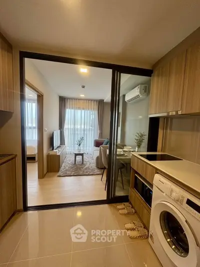 Modern apartment with open layout, featuring a cozy living room and kitchen with washing machine.