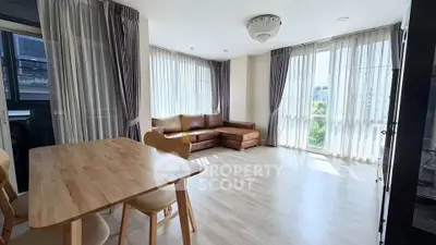 Spacious living room with large windows and modern furniture in a bright apartment.