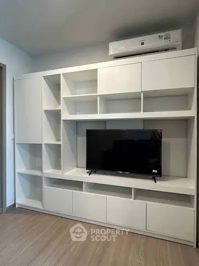 Modern living room with sleek white shelving and mounted TV, perfect for stylish urban living.
