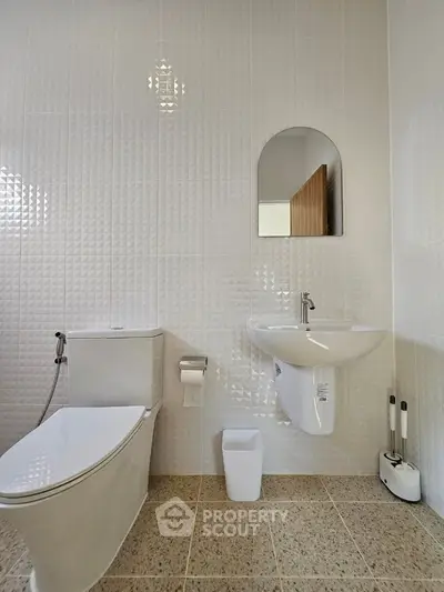 Modern bathroom with sleek fixtures and textured wall tiles, featuring a compact sink and toilet.