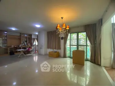 Spacious living room with chandelier and large windows, perfect for natural light.