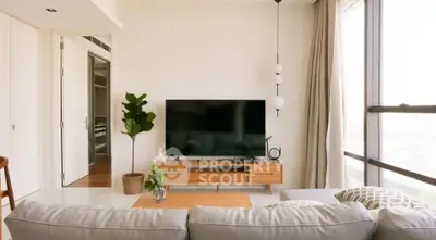 Modern living room with large TV, stylish furniture, and natural light from floor-to-ceiling windows.