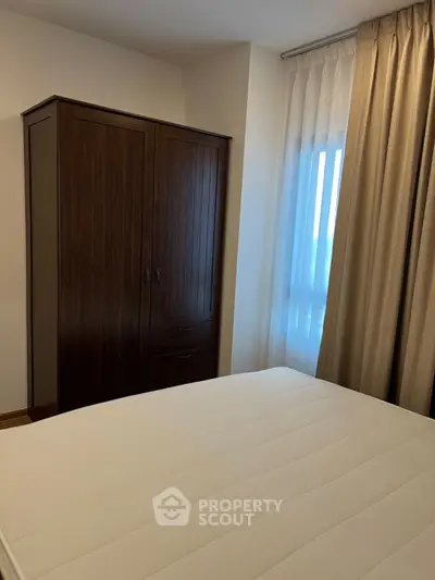 Cozy bedroom with wooden wardrobe and large window with curtains
