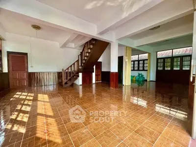 Spacious open-plan living area with wooden staircase and large windows