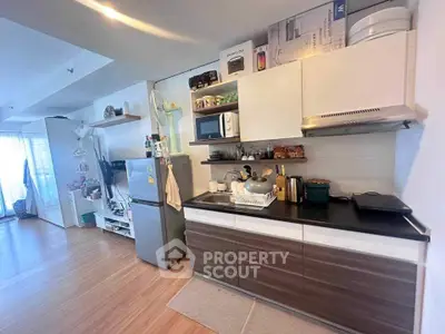 Modern kitchen with sleek cabinets and appliances in open layout apartment.