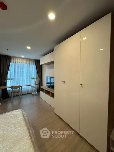 Modern bedroom with sleek wardrobe and large window in a stylish apartment.