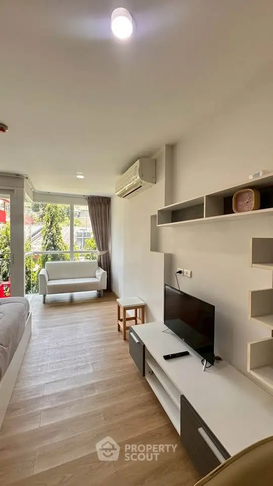 Modern living room with natural light, featuring sleek furniture and a view of greenery.