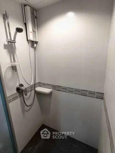 Compact bathroom with modern shower and water heater in sleek tiled design.