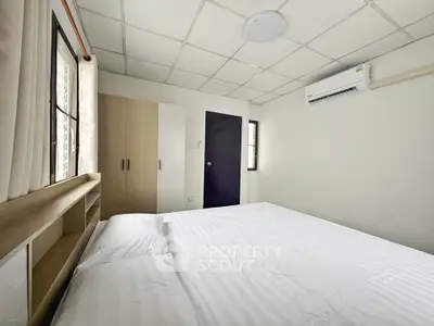 Cozy bedroom with modern air conditioning and ample natural light, perfect for relaxation and comfort.
