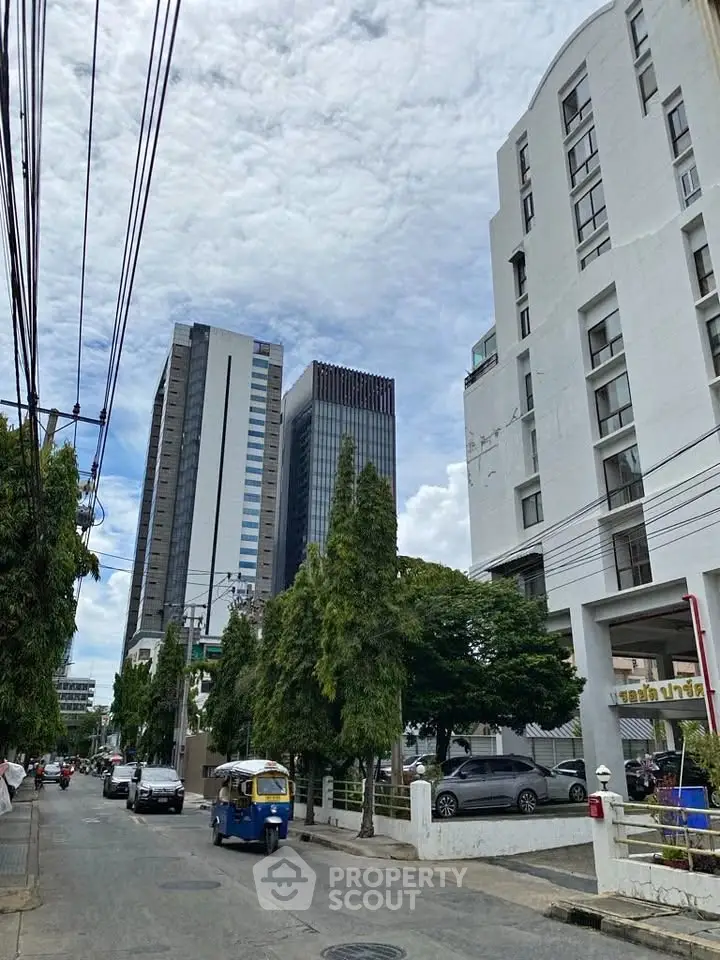 Urban street view with modern high-rise buildings and lush greenery.