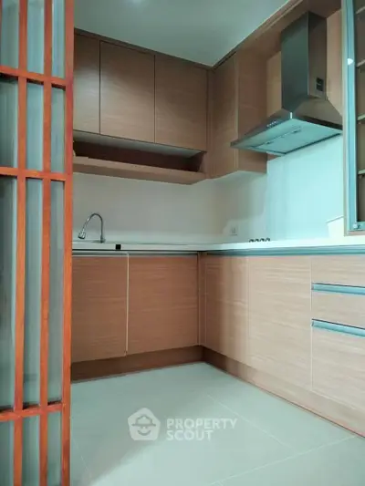 Modern kitchen with sleek wooden cabinets and stainless steel range hood