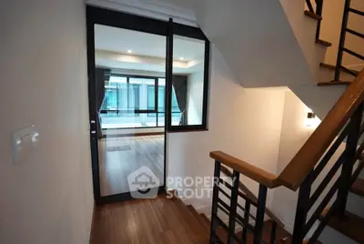 Modern staircase leading to a spacious living area with large windows and wooden flooring.